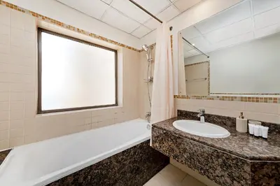 a bathroom with a sink and a tub and a window at Excellent 1BR Apertments at Bahar 6 in Dubai