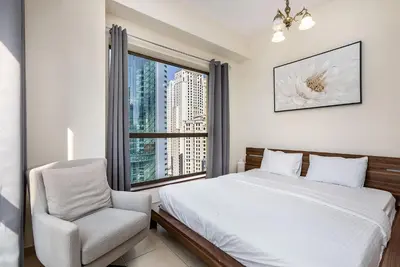a bedroom with a bed and a chair and a window at Excellent 1BR Apertments at Bahar 6 in Dubai
