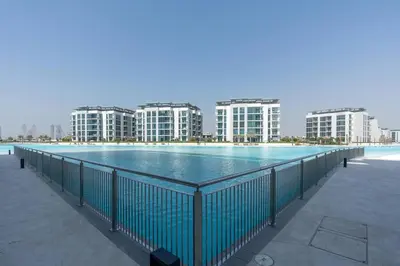 a large swimming pool with buildings in the background at One Bedroom - 10min from Burj Khalifa - Lagoon View in Dubai