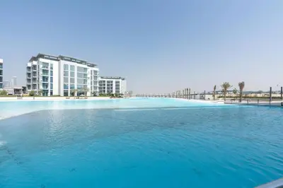 a large swimming pool with a building in the background at One Bedroom - 10min from Burj Khalifa - Lagoon View in Dubai