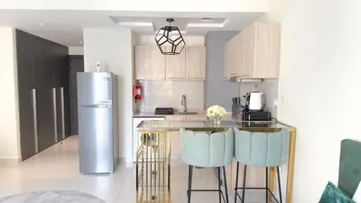 a kitchen with a refrigerator and a counter with stools at Ahlan HH - Charming Studio at AG Tower in Dubai