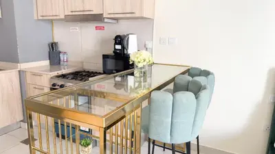 a kitchen with a glass counter and two blue chairs at Ahlan HH - Charming Studio at AG Tower in Dubai