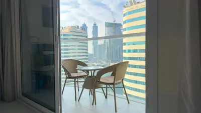 a table and chairs on a balcony with a view of a city at Ahlan HH - Charming Studio at AG Tower in Dubai