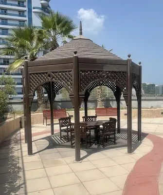 a wooden gazebo with a table and chairs at Marina view with Pool, Gym, Tennis Court, 5 mins to Beach in Dubai