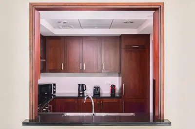 a kitchen with wooden cabinets and a sink at BellaVista - Graceful - 1 BR - 29 Boulevard - with Burj Khalifa View in Dubai
