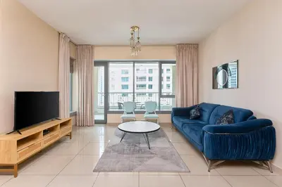 a living room with a blue couch and a tv at BellaVista - Graceful - 1 BR - 29 Boulevard - with Burj Khalifa View in Dubai