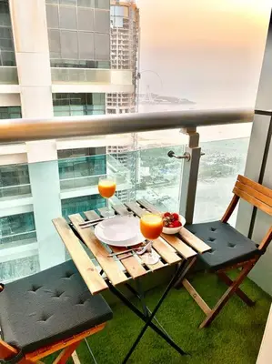 a balcony with a table and two glasses of orange juice at Your Cosy Dubai Marina Home in Dubai