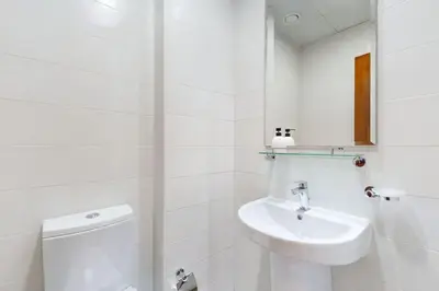 a white bathroom with a toilet and a sink at Vacationer l Premium One Bed I Walk to Dubai Mall, Burj Khalifa I Dunya Tower Downtown in Dubai