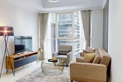 a living room with a couch and a tv at Vacationer l Premium One Bed I Walk to Dubai Mall, Burj Khalifa I Dunya Tower Downtown in Dubai