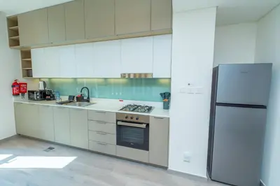 a kitchen with white cabinets and a refrigerator at Midtown Haven Cozy One Bed in Dubai in Dubai