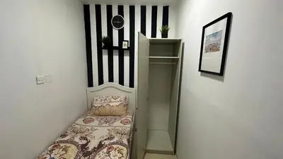 a small bedroom with a bed and a shelf at Solo Partition Room in Al Barsha 1 Near Mashreq Metro in Dubai
