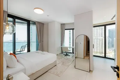 a bedroom with a large white bed and glass windows at Address JBR with Sea View & Maid Room - Mint Stay in Dubai