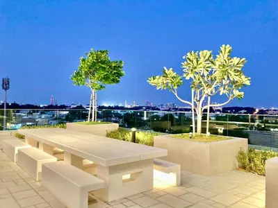 a white table and benches on a balcony with trees at Luxurious 1-bedroom With Skyline View In Downtown Views Ii in Dubai