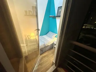 a small bedroom with a bed and a glass door at Cityview Partition Room with Balcony in Tecom in Dubai