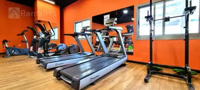 an orange gym with three tread machines in a room at Luxury Studio w/ BoHo Design and Balcony for 4 Pax in Dubai