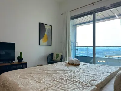 a bedroom with a large bed and a large window at Luxury Studio w/ BoHo Design and Balcony for 4 Pax in Dubai