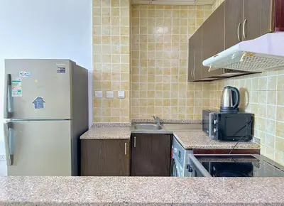 a kitchen with a refrigerator and a sink at Luxury Studio w/ BoHo Design and Balcony for 4 Pax in Dubai