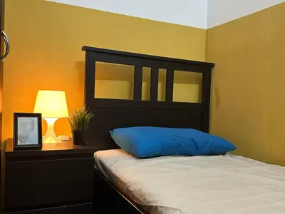 a bedroom with a bed with a blue pillow and a lamp at Cozy Partition Room Near Mashreq & MOE Metro in Dubai