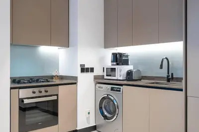 a kitchen with a washing machine and a microwave at Ranch Living 1 bedroom apartment in Business Bay by Suiteable in Dubai