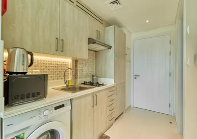 a kitchen with a sink and a washing machine at First Class Apartments in Seven Palm with direct Access to the West Palm Beach and Nakheel Mall in Dubai
