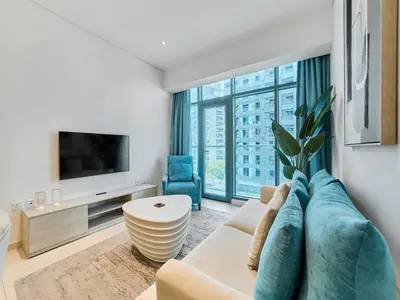 a living room with a couch and a tv at First Class Apartments in Seven Palm with direct Access to the West Palm Beach and Nakheel Mall in Dubai