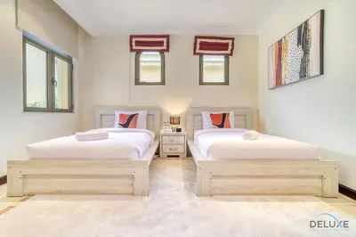 two twin beds in a room with windows at Premier 6BR Villa with Assistant's Room and Private Pool in Frond E Palm Jumeirah by Deluxe Holiday Homes in Dubai