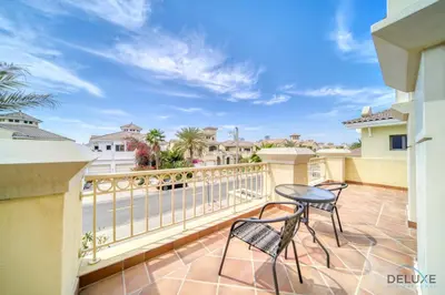 a balcony with two chairs and a table at Premier 6BR Villa with Assistant's Room and Private Pool in Frond E Palm Jumeirah by Deluxe Holiday Homes in Dubai