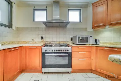 a kitchen with a stove and a microwave at Premier 6BR Villa with Assistant's Room and Private Pool in Frond E Palm Jumeirah by Deluxe Holiday Homes in Dubai