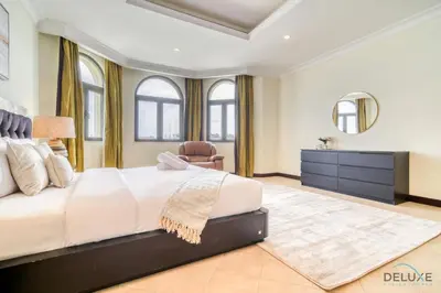 a bedroom with a large bed and a dresser at Premier 6BR Villa with Assistant's Room and Private Pool in Frond E Palm Jumeirah by Deluxe Holiday Homes in Dubai