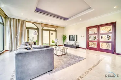 a living room with a couch and a tv at Premier 6BR Villa with Assistant's Room and Private Pool in Frond E Palm Jumeirah by Deluxe Holiday Homes in Dubai