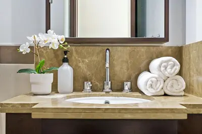 a bathroom sink with towels and a vase of flowers at Cute 1 BR - Walk to Opera, Mall & Burj Khalifa in Dubai