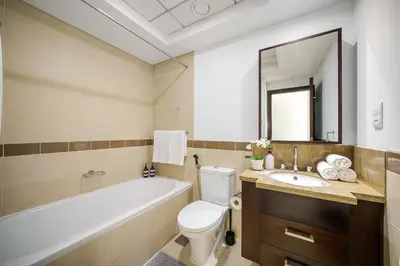a bathroom with a tub and a toilet and a sink at Cute 1 BR - Walk to Opera, Mall & Burj Khalifa in Dubai
