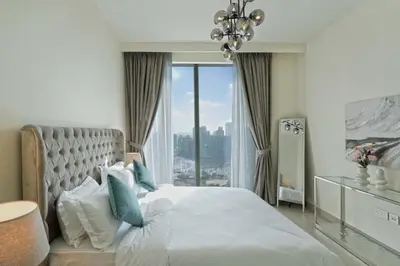 a bedroom with a large bed with a chandelier at Chic 2-Bedroom Downtown Gem in Dubai