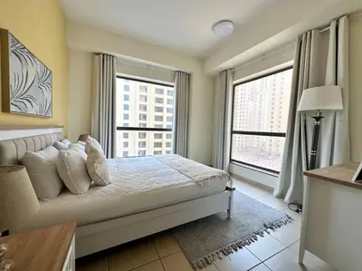 a bedroom with a bed and two large windows at Sun, Sand, and FUN - King Bed, Sofa Bed! Sleeps 4 in Dubai