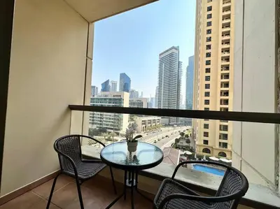 a table and chairs on a balcony with a view of a city at Sun, Sand, and FUN - King Bed, Sofa Bed! Sleeps 4 in Dubai