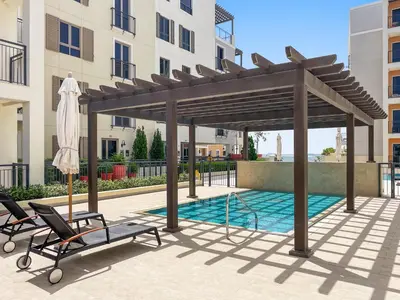a wooden pergola with two chairs and a pool at Spacious 1 bed in La Mer - 1 min to the beach in Dubai