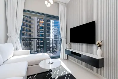 a living room with a white couch and a flat screen tv at Stylish Apartment in Dubai