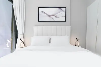 a bedroom with two white beds and a picture on the wall at Stylish Apartment in Dubai