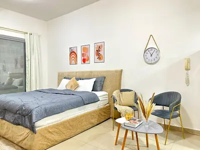 a bedroom with a bed and a chair and a clock at Comfy Studio w/ Balcony & Nice Design in Marina in Dubai
