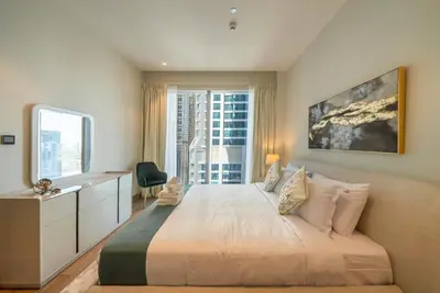 a bedroom with a bed with a desk and a window at Luton Vacation Homes - Tranquil 2BR Haven in the Heart of Dubai Marina- 28AB04 in Dubai