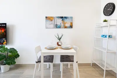 a white dining room table with chairs and a clock at Cozy Studio 29th Floor, Bloom Towers Marina View in Dubai