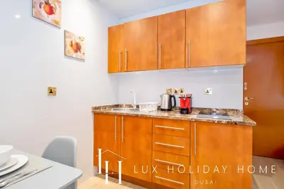 a kitchen with wooden cabinets and a counter top at LUX The Marina View Suite 2 in Dubai