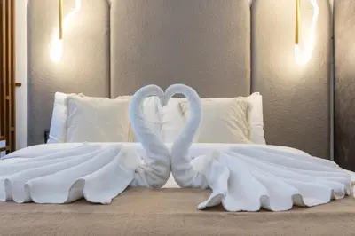 two swansuitsrendered to look like they are kissing on a bed at Nice Studio in heart of JVC - Pantheon Elysée - Dubai in Dubai