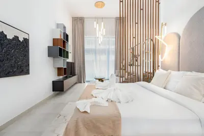 a bedroom with a large white bed and a chandelier at Nice Studio in heart of JVC - Pantheon Elysée - Dubai in Dubai