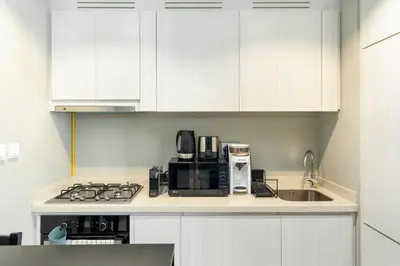a kitchen with white cabinets and a stove and a sink at 1 Bedroom in Zada Tower - Business Bay - Dubai in Dubai