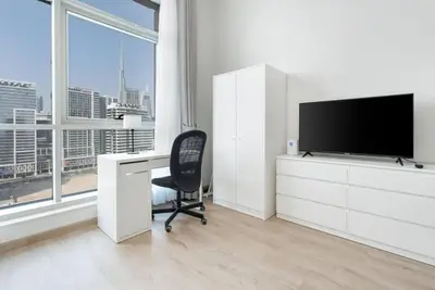 a white office with a desk and a television at Studio with Burj Khalifa View in Dubai