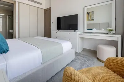 a white bedroom with a bed and a tv at Frank Porter - Bluebell Residence in Dubai