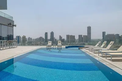 a large swimming pool with lounge chairs on a building at Frank Porter - Bluebell Residence JVC in Dubai