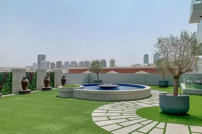 a garden with a fountain in the middle of a lawn at Frank Porter - Bluebell Residence JVC in Dubai