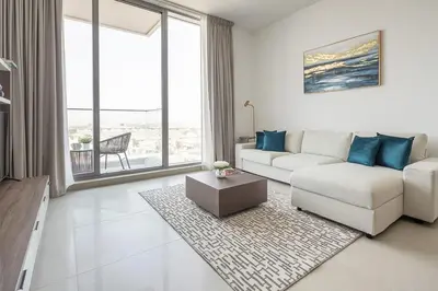 a white living room with a white couch and blue pillows at Frank Porter - Bluebell Residence JVC in Dubai
